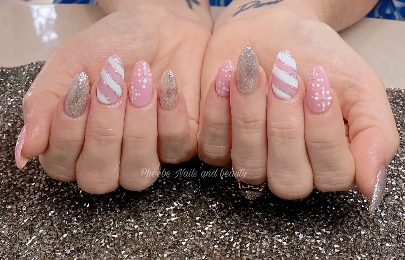 Pink and silver glitter almond nails with candy-stripe and snowflake accents