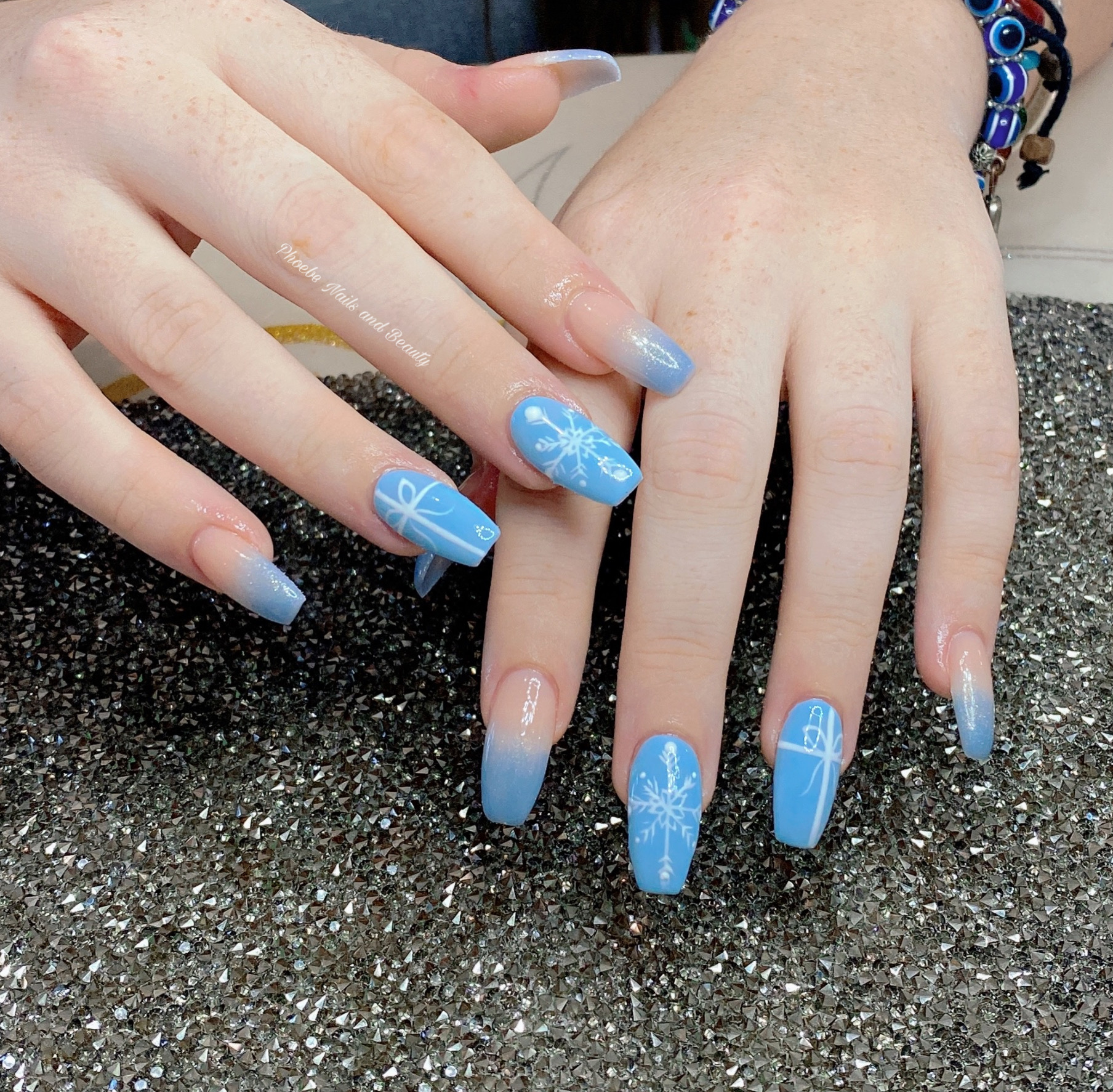 Coffin nails fading from nude to baby blue with painted gift boxes and snowflakes