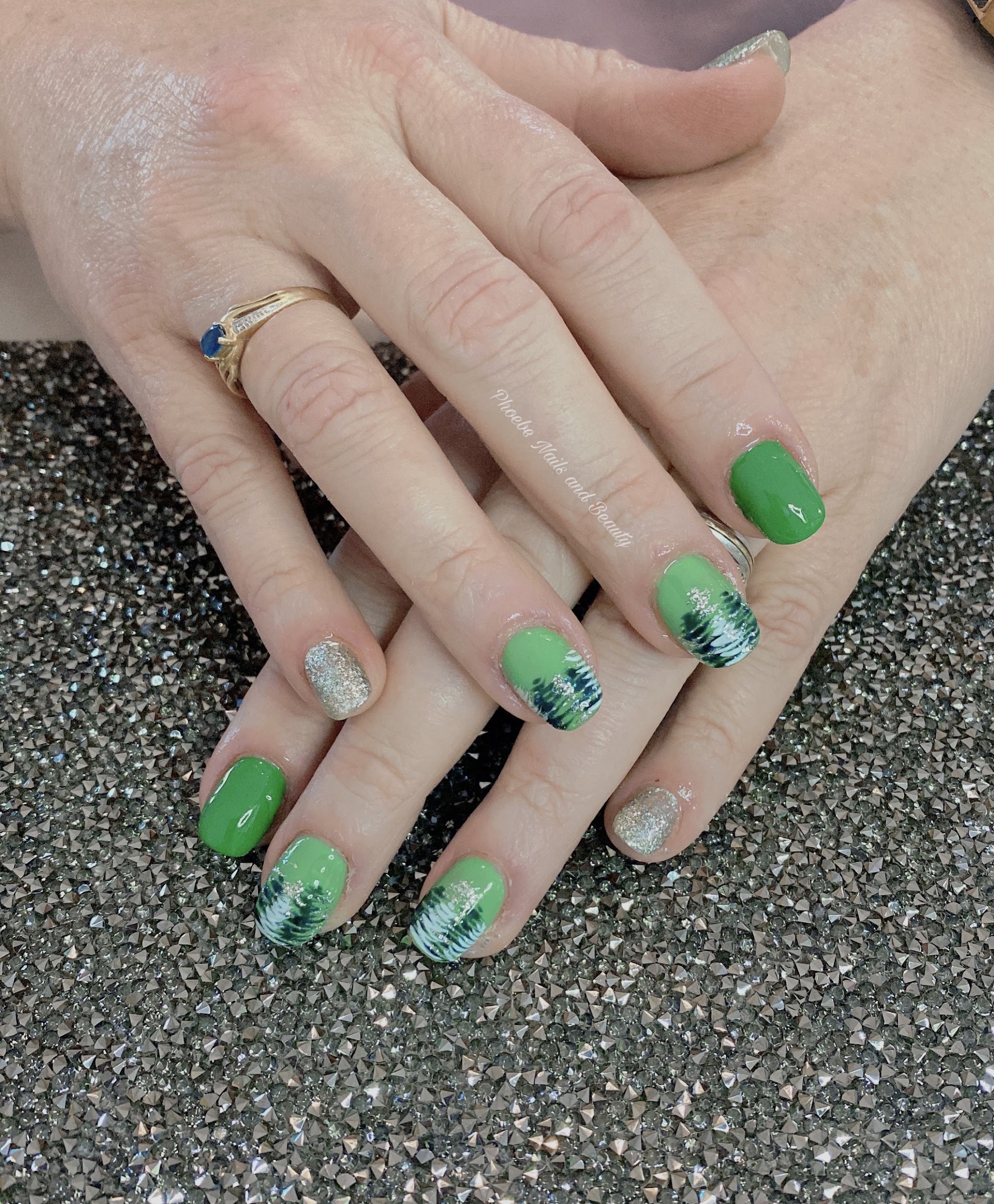 Green gel nails with silver glitter and hand-painted pine trees