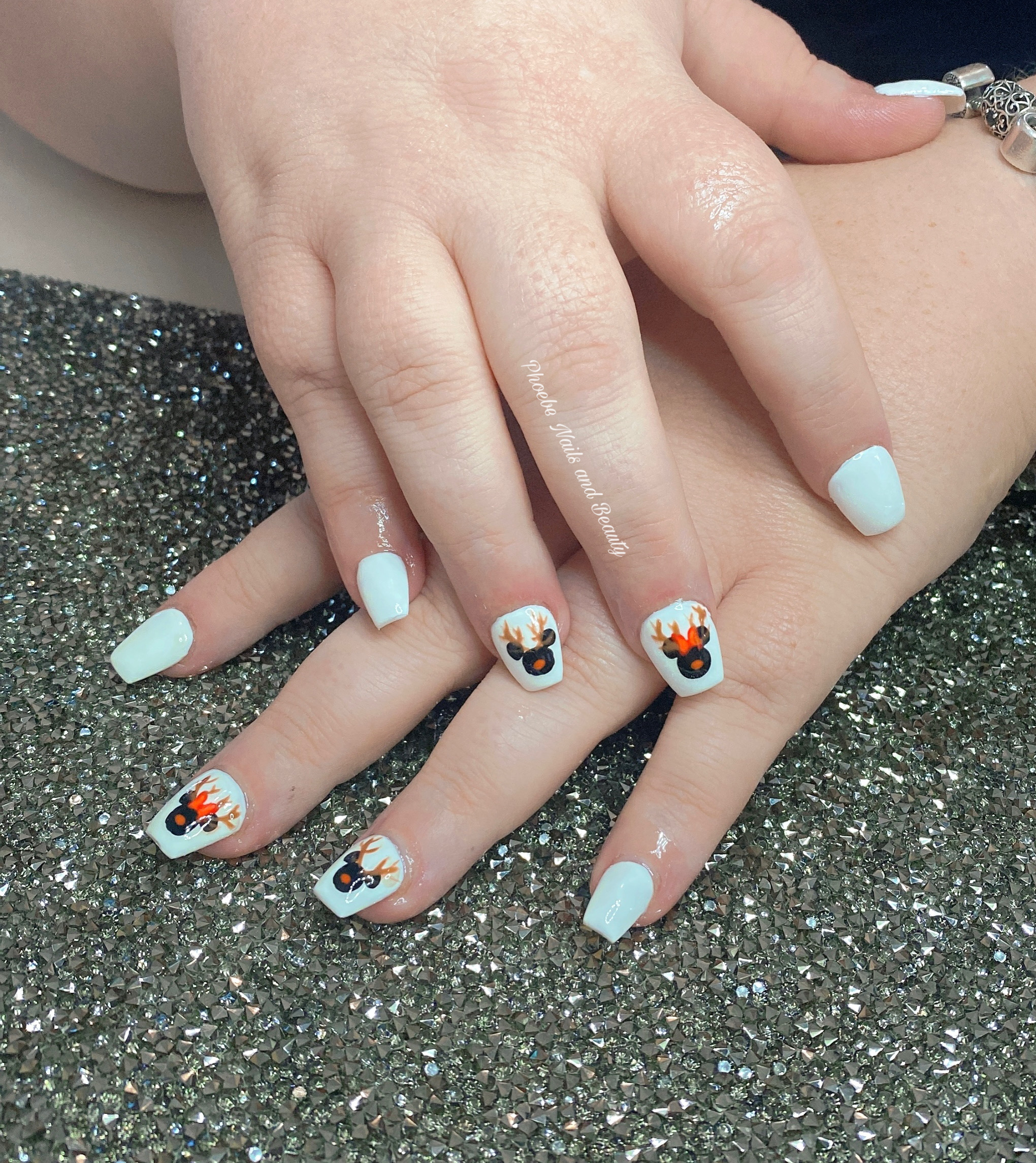 White square nails with little painted reindeer faces on the accent nails